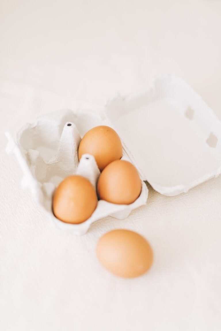 Brown eggs in an open carton against a soft background, highlighting simplicity and freshness.