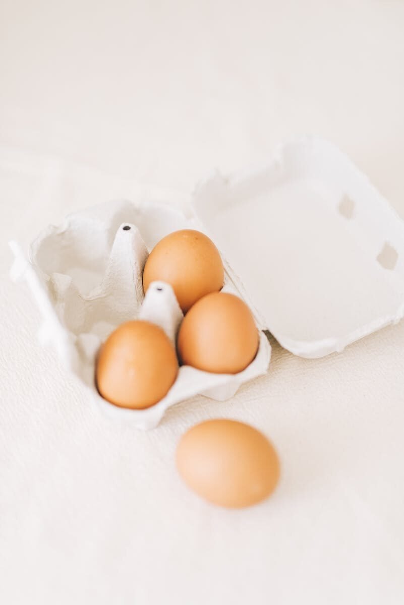 Brown eggs in an open carton against a soft background, highlighting simplicity and freshness.