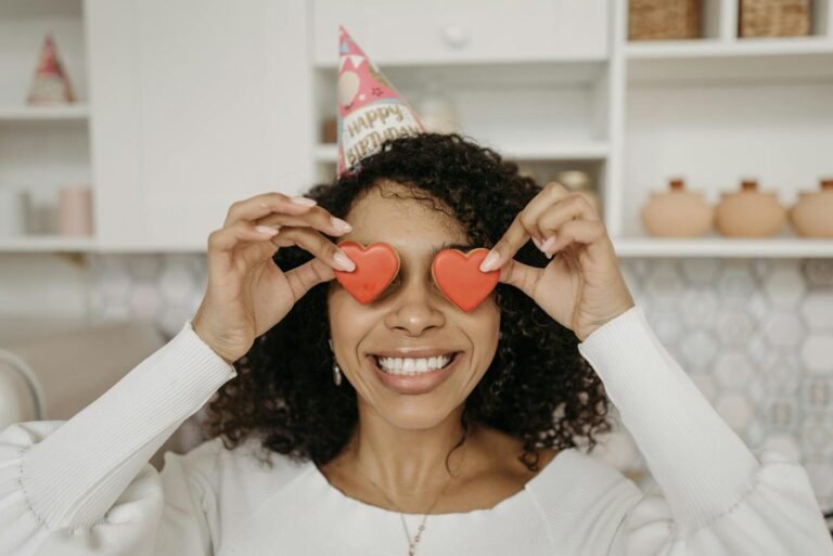 Joyful woman with heart-shaped candies celebrates her birthday indoors.