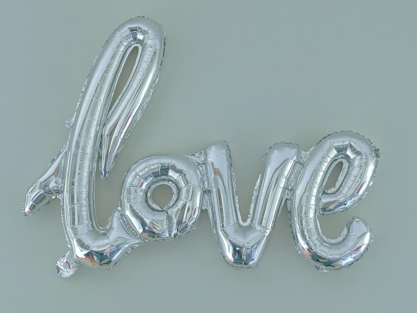 Silver balloon letters spelling 'love' on a light background, perfect for party decor.