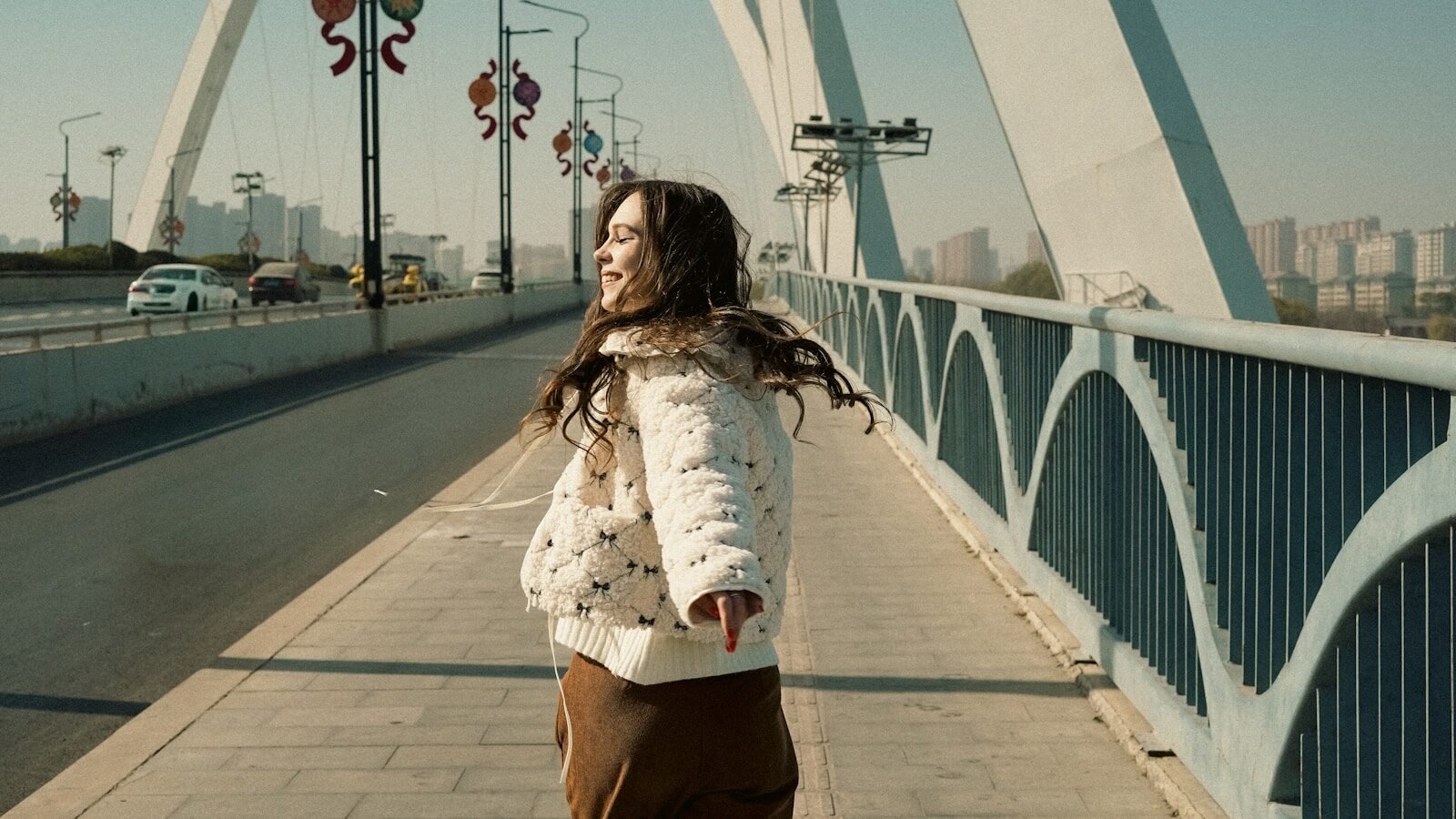 Young woman walking on a bridge with city skyline